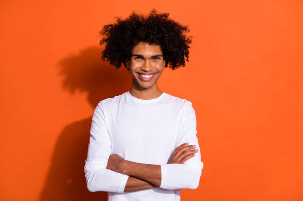 Photo of funky pretty guy dressed white shirt arms crossed smiling isolated orange color background. - Фото, изображение