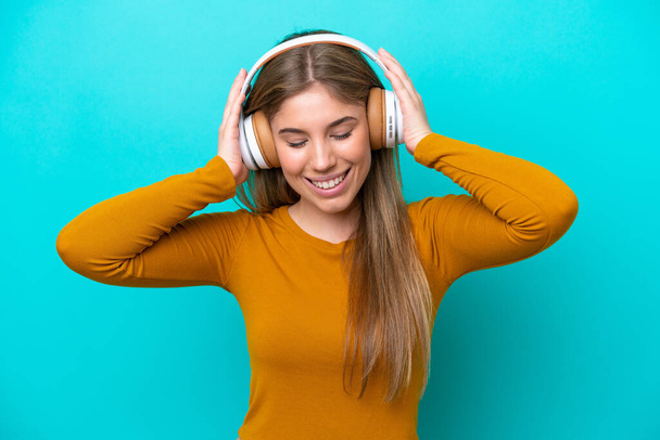 Молода біла жінка ізольована на синьому фоні прослуховування музики
 - Фото, зображення
