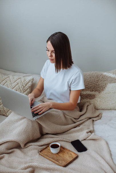 Young woman working on laptop at home in bed - Фото, зображення