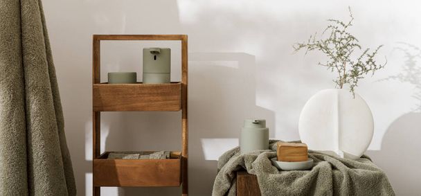Moderne ästhetische Badezimmeraccessoires in Eukalyptus hellgrünen Farbton. Badetücher aus Bio-Baumwolle, minimalistische Vase im skandinavischen Stil, Sensorseife und Lotionspender auf massivem Eichenstumpf. Tägliche Körperpflege, Spa- und Wellness-Badezimmerkonzept - Foto, Bild
