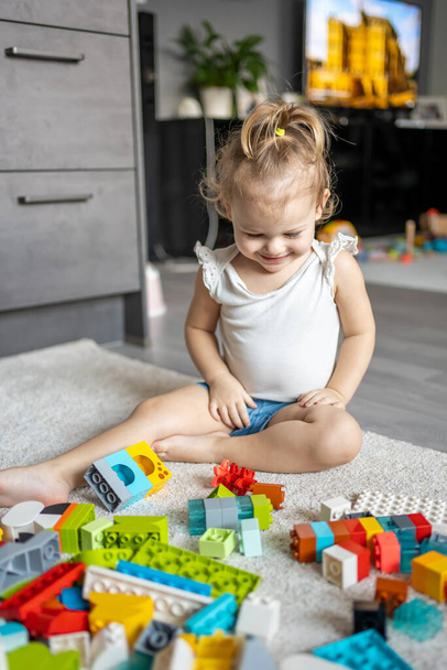 Caucasian child a little girl is playing in the constructor at home. Educational toys for children. - Foto, imagen