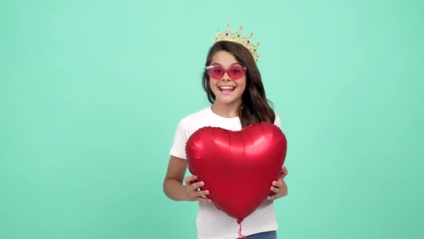 encantador niño sorprendido en gafas de sol y corona reina con globo de fiesta de corazón, sorpresa - Metraje, vídeo