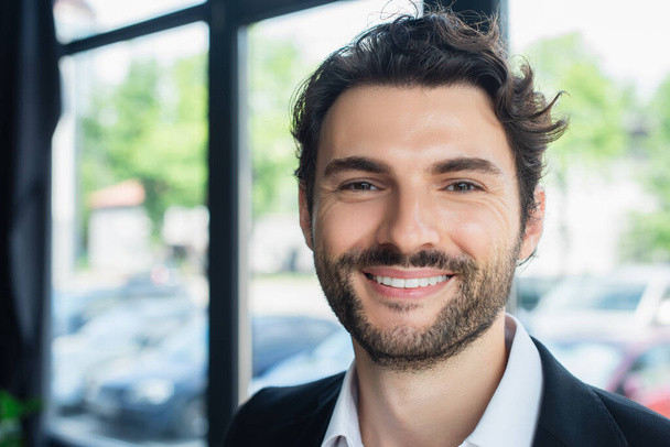 portrait of cheerful brunette businessman looking at camera in office - Photo, image