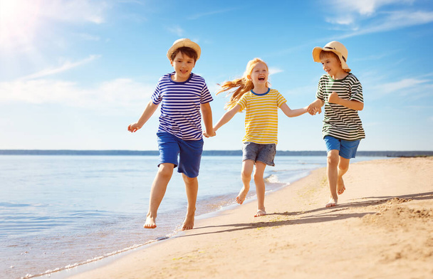 Χαριτωμένα παιδιά τρέχουν κατά μήκος της ακτής της θάλασσας - Φωτογραφία, εικόνα