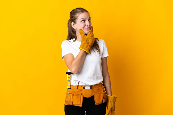 Nuori sähköasentaja nainen eristetty keltaisella taustalla, jolla on epäilyksiä ja sekava ilme - Valokuva, kuva