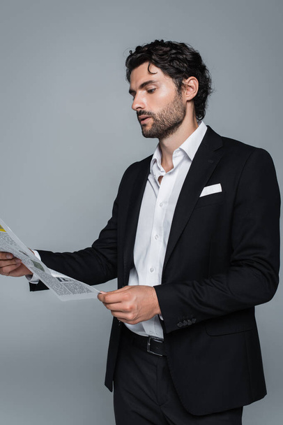 homme d'affaires en blazer noir et chemise blanche lecture journal isolé sur gris - Photo, image