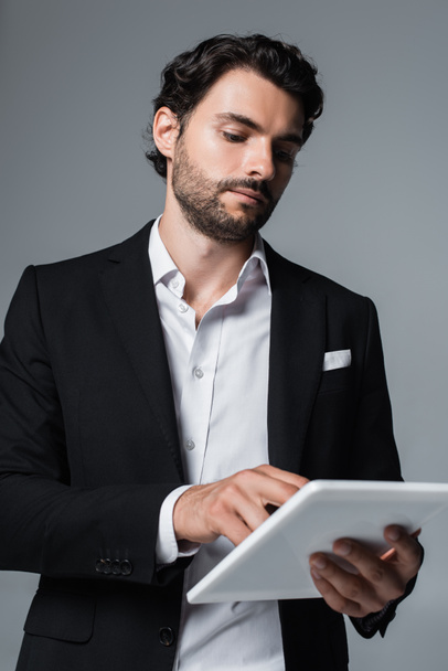 homme d'affaires en blazer noir et chemise blanche en utilisant une tablette numérique isolée sur gris - Photo, image