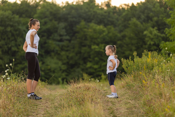 mom and daughter doing exercise in nature - Photo, Image