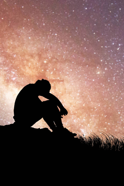Un hombre se sienta decepcionado en el amor con la Vía Láctea y estrellas en el fondo. concepto de pérdida, soledad, decepción - Foto, Imagen