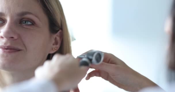 Lekarz laryngolog przeprowadza badanie ucha z otoskopem zbliżenie - Materiał filmowy, wideo