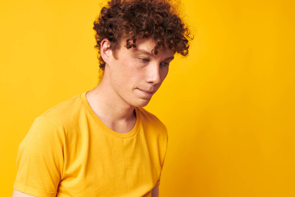 Mladý kudrnatý muž Mládež styl studio příležitostné oblečení žluté pozadí beze změny - Fotografie, Obrázek
