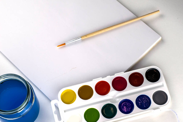 watercolor paints brush jar with water and sketchbook on a white background. High quality photo - Photo, Image