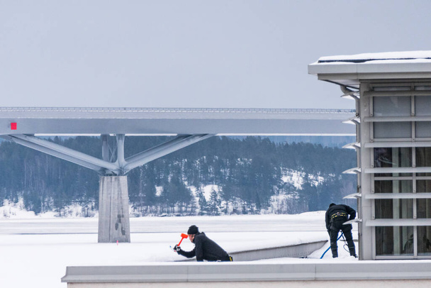 Sundsvall, Sweden Two men remove ice and snow fron the roof of a building. - Foto, Bild