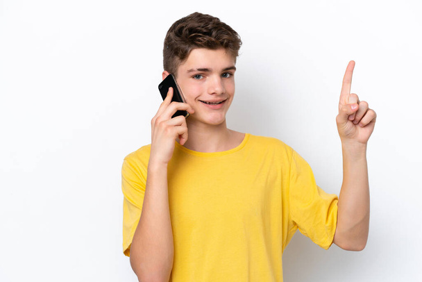 Teenager man using mobile phone isolated on white background pointing up a great idea - Foto, immagini
