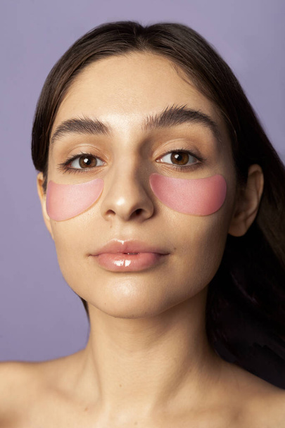 beautiful girl with pink eye patches on a lilac background - Foto, Bild