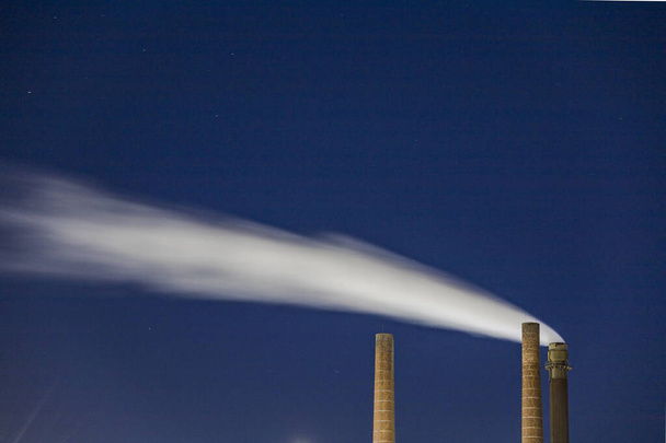 Sundsvall, Svédország Feb 9, 2022 Industrial smokestacks at night at a paper mill. - Fotó, kép