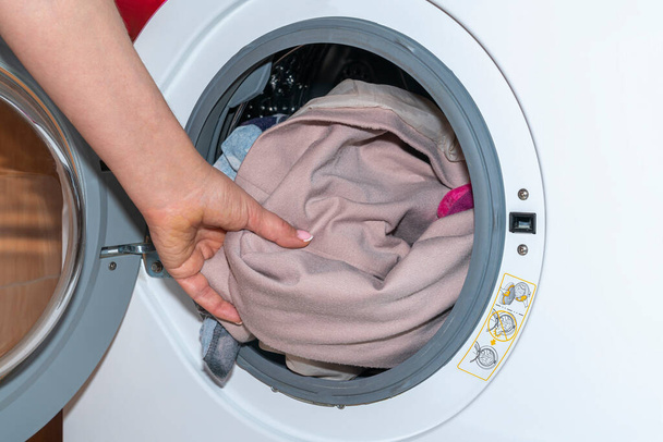 Eine Frauenhand holt die Wäsche aus der Waschmaschine - Foto, Bild
