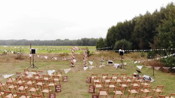 Widok z lotu ptaka otwartej przestrzeni urządzone do ceremonii ślubnej z rzędami krzeseł i łuku kwiatowego - Materiał filmowy, wideo