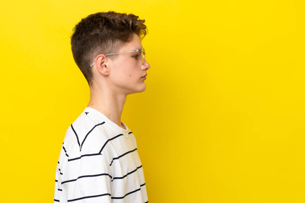 Teenager Russian man isolated on yellow background With glasses - Photo, Image