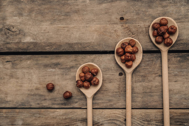 shelled hazelnuts in spoon on wooden background, close up - Fotoğraf, Görsel