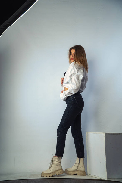 Foto von jungen schönen sinnlichen und sexy Frau mit langen Haaren trägt in weißem Hemd posiert vor einer weißen Wand im Studio.   - Foto, Bild