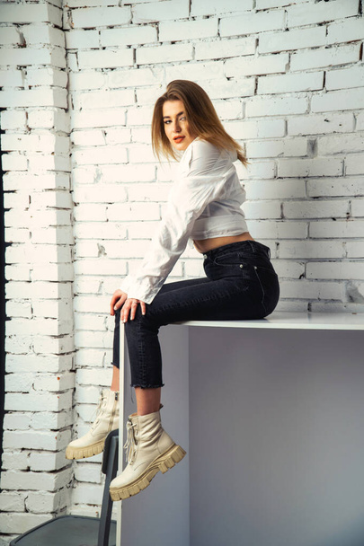 Photo de jeune belle femme sensuelle et sexy aux cheveux longs portant une chemise blanche posant contre un mur de briques blanches en studio.   - Photo, image