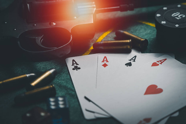 Nahaufnahme beim Spielen von Chips, Spielkarten, Gewehren und Kugeln. Casino Pokerspiel-Konzept. Spielkarten, Pokerchips und Würfel am grünen Tisch. der Blick von oben - Foto, Bild