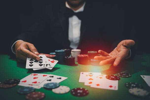 Adam satıcı ya da krupiye kumarhane kartına poker kartı karıştırıyor ve yeşil masaya da fiş koyuyor. Poker oyunu konsepti - Fotoğraf, Görsel