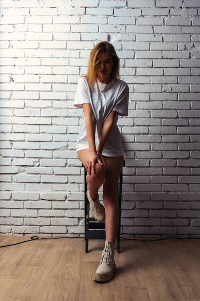 Foto di giovane bella donna sensuale e sexy con i capelli lunghi che indossa in t-shirt posa contro un muro bianco in studio.   - Foto, immagini