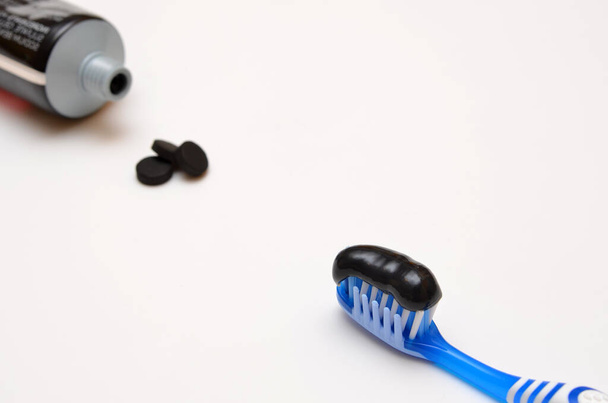 pasta de dientes negra y carbón activado sobre un fondo blanco - Foto, Imagen