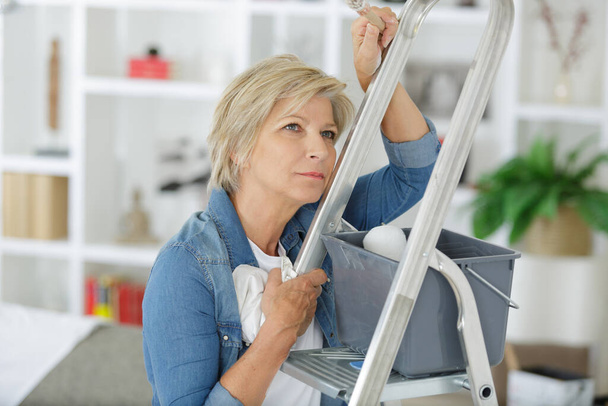 mature woman looking daunted by her redecorating job - Foto, Imagen