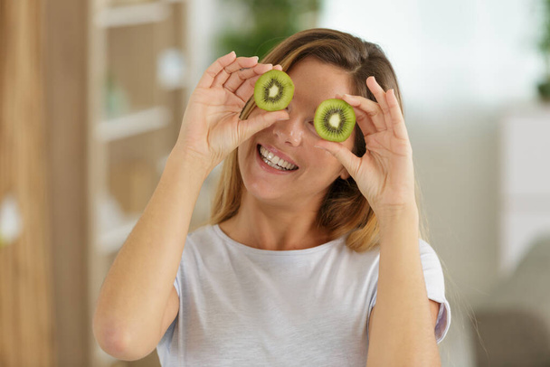 beautiful young woman using kiwis on her face - 写真・画像