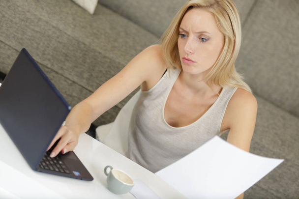 woman reading a contract with a laptop beside - Foto, imagen