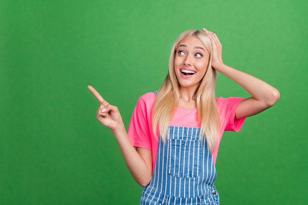 Photo of excited crazy lady direct fingers empty space discount banner wear striped overall isolated green color background - 写真・画像