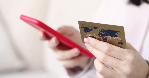 Mujer mano sostiene teléfono celular rojo tarjeta bancaria de primer plano - Imágenes, Vídeo