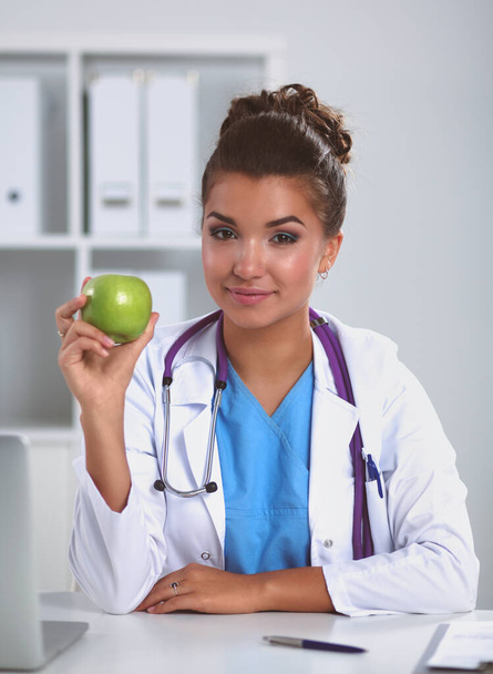 Female doctor hand holding a green apple, sitting - Фото, изображение