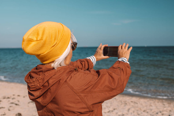 Woman taking pictures with phone outdoors, exploring the coast. Enjoying the nature - Фото, зображення