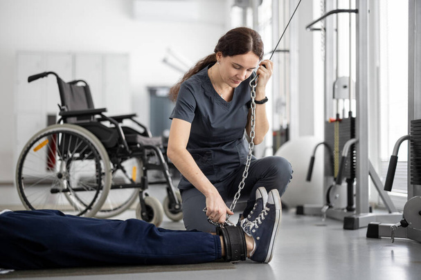Rehabilitační specialista pomáhá člověku cvičit na dekompresním simulátoru pro zotavení - Fotografie, Obrázek