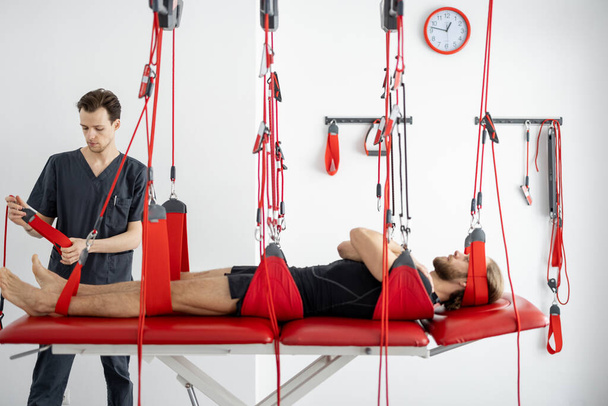 Spécialiste en réadaptation se préparant à un traitement actif sur sangles de suspension avec un patient de sexe masculin - Photo, image