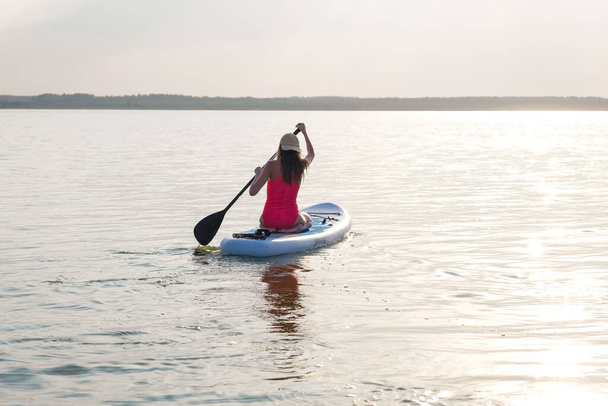 Young female paddle boarding at sunset. - Fotografie, Obrázek