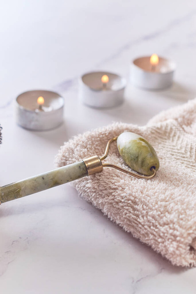jade facial roller on white marble table. Flat lay, spa concept - Photo, Image
