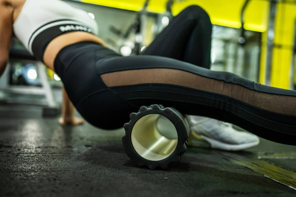 Nainen käyttäen mustaa vaahto Roller lihaksen ja Fascia Venyttely jalka - Nainen urheilija lievittää kipeä lihaksia harjoittelun jälkeen kuntosalilla - terveys ja kunto urheilu kehon hoito käsite lähikuva jalka - Valokuva, kuva