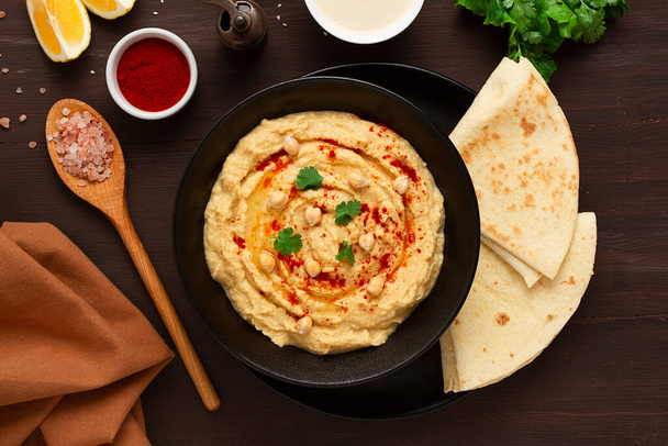 Classic chickpea hummus with tahini, olive oil, garlic and paprika, homemade, on a black background, top view, no people, - Fotó, kép