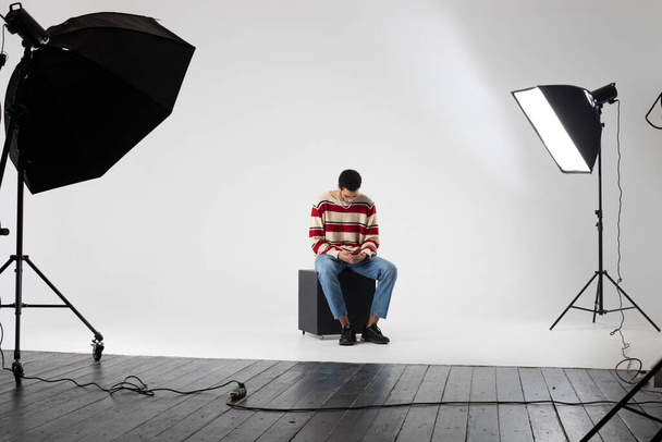 Young african american man in a striped sweater on a white background in a photo studio. - Zdjęcie, obraz