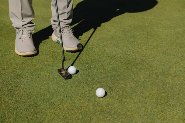 Szczegóły stóp męskiego golfisty grającego w piłkę na zielonej trawie. - Zdjęcie, obraz