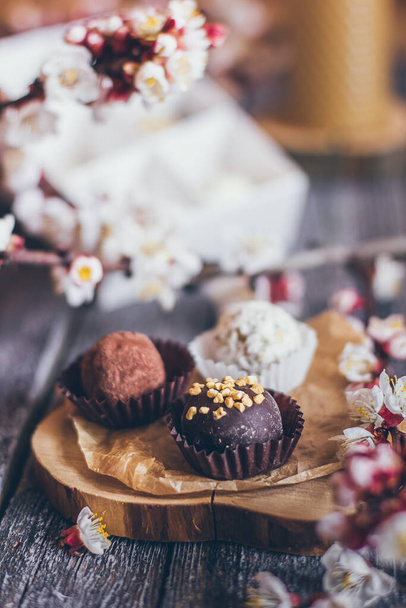 Bahar koleksiyonunda el yapımı çikolatalı şekerler ve kiraz çiçekleri kırsal ahşap arka planda süslemeler. - Fotoğraf, Görsel