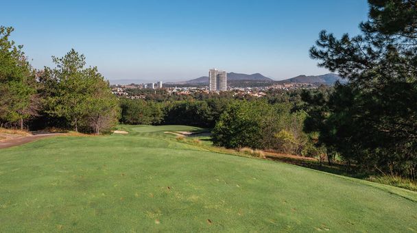 Пейзаж поля для гольфа с короткой зеленой травой, холмами и деревьями. - Фото, изображение