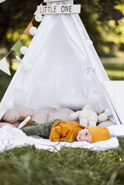 Happy baby boy lying inside teepee tent outdoors - Фото, зображення