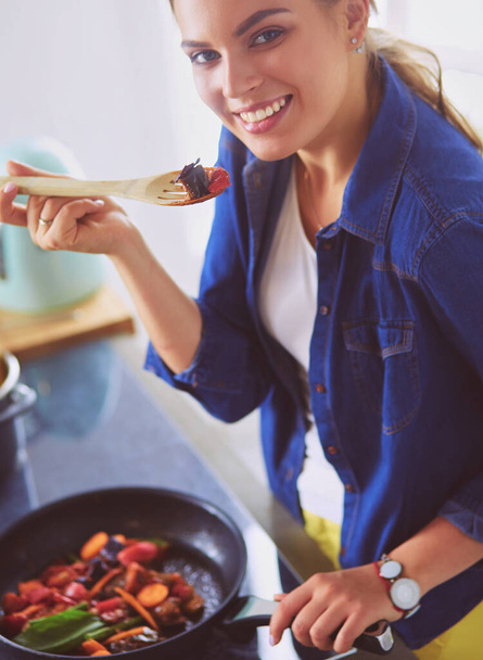 Mujer joven cocinando alimentos saludables sosteniendo una sartén con verduras es. Estilo de vida saludable, cocina en casa concepto - Foto, Imagen