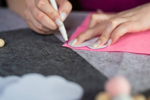 Vrouwen handen maken een hartpatroon op roze vilt. Stap-voor-stap instructies voor het maken van handgemaakte producten van vilt. stap 1.Mobiel in de wieg - Foto, afbeelding
